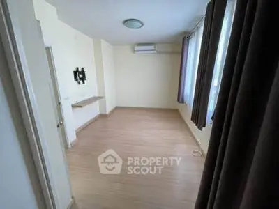 Spacious empty room with wooden flooring and large windows, ideal for customization.