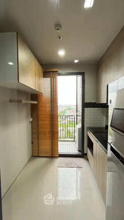 Modern kitchen with sleek design and balcony view, featuring built-in appliances and ample storage.