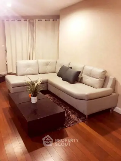 Elegant living room with modern sectional sofa and stylish coffee table on hardwood floor.