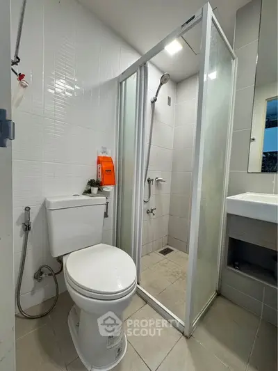 Modern bathroom with shower cabin and toilet in compact space.