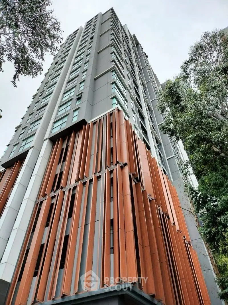 Modern high-rise building with unique architectural design and lush greenery surroundings.