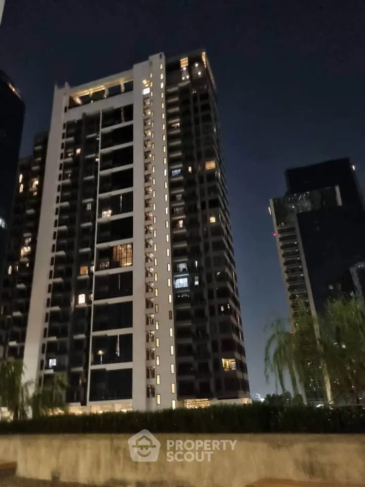 Stunning night view of modern high-rise residential building with illuminated windows and urban skyline.