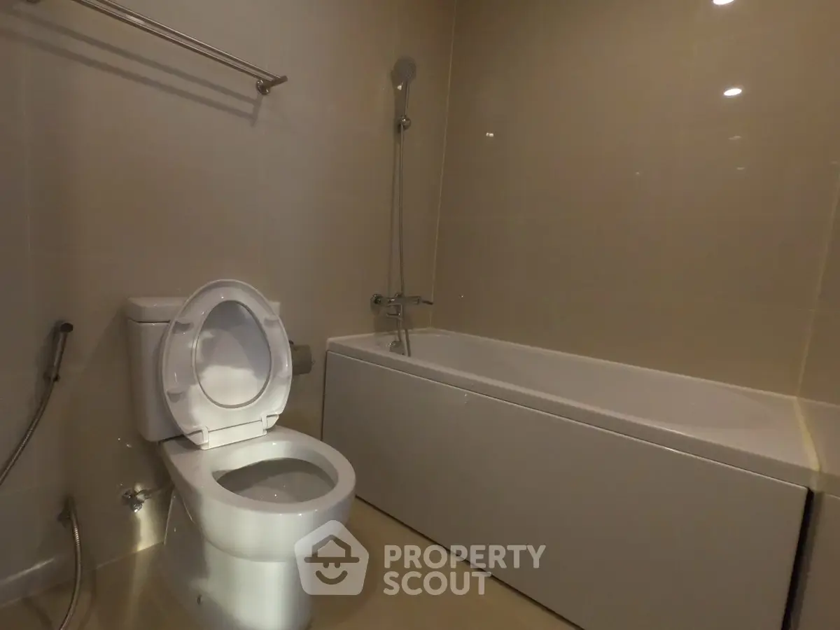 Modern bathroom with sleek bathtub and toilet in a contemporary apartment.