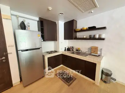 Modern kitchen with stainless steel fridge and open shelving in cozy apartment
