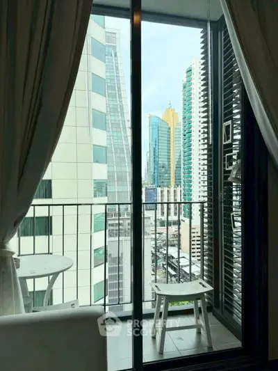 Modern city view from a stylish balcony with glass doors and cozy seating area.