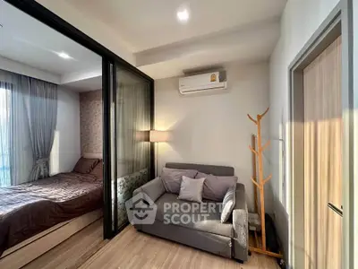 Cozy bedroom with modern decor and natural light, featuring a comfortable sofa and stylish coat rack.