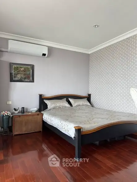 Spacious bedroom with elegant wooden flooring and modern air conditioning unit.