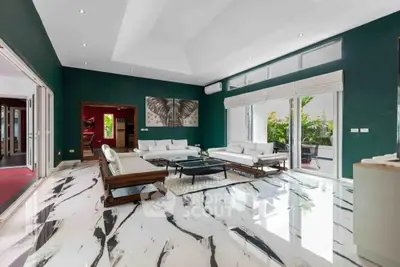 Luxurious modern living room with marble flooring and elegant furniture, featuring large windows and lush garden view.