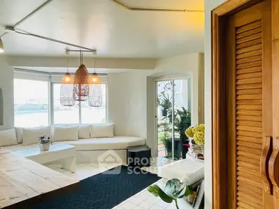 Bright living room with large windows and cozy seating area, perfect for relaxation.