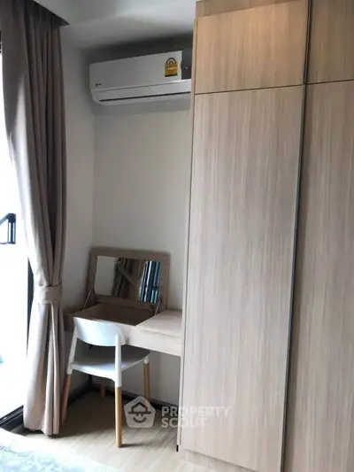 Cozy study nook with wooden desk and chair, complemented by a sleek wardrobe and air conditioning.