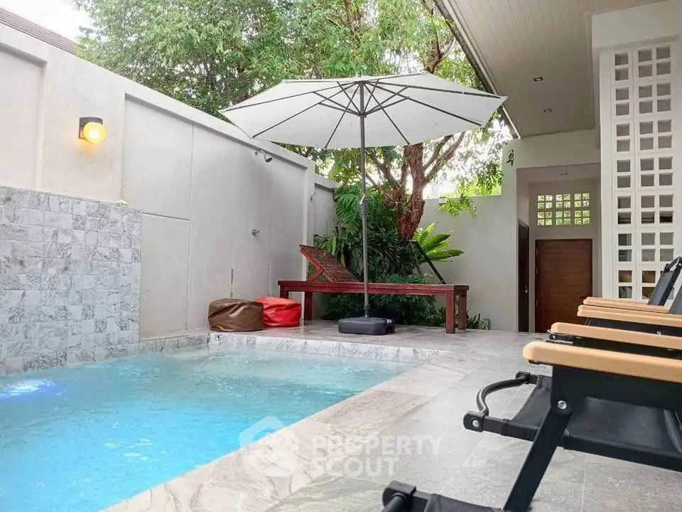 Chic outdoor pool area with modern seating and lush greenery, perfect for relaxation and entertainment.