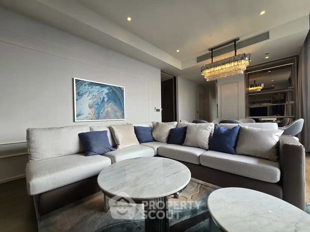 Luxurious living room with elegant chandelier and plush sectional sofa in modern apartment.