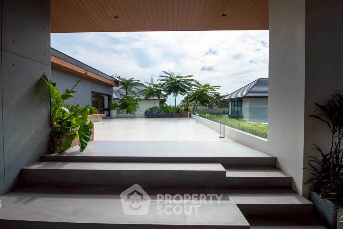 Luxurious modern home entrance with spacious patio and lush greenery, perfect for serene living.
