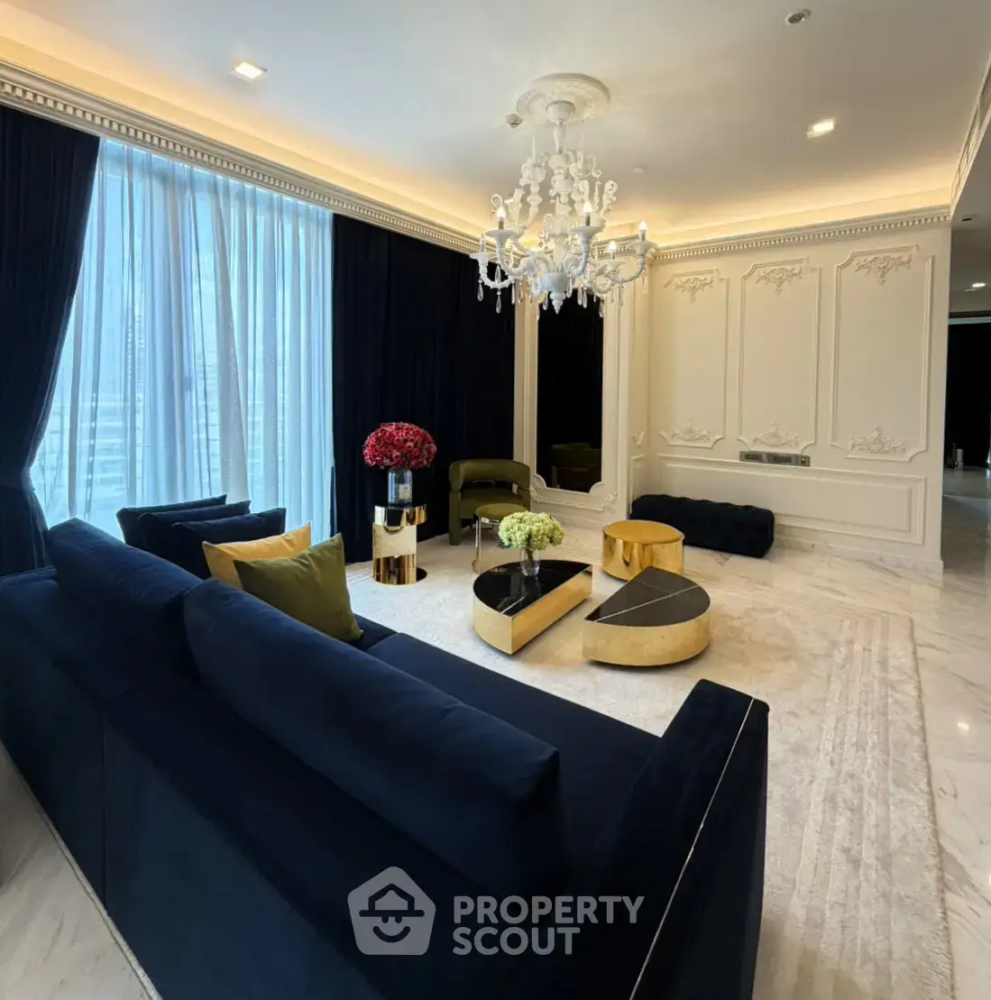 Luxurious living room with elegant chandelier and plush navy sofas in a sophisticated setting.