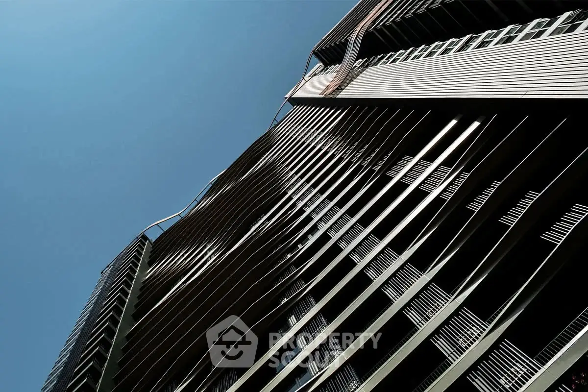 Stunning modern architectural facade with sleek lines and dynamic design against clear blue sky.