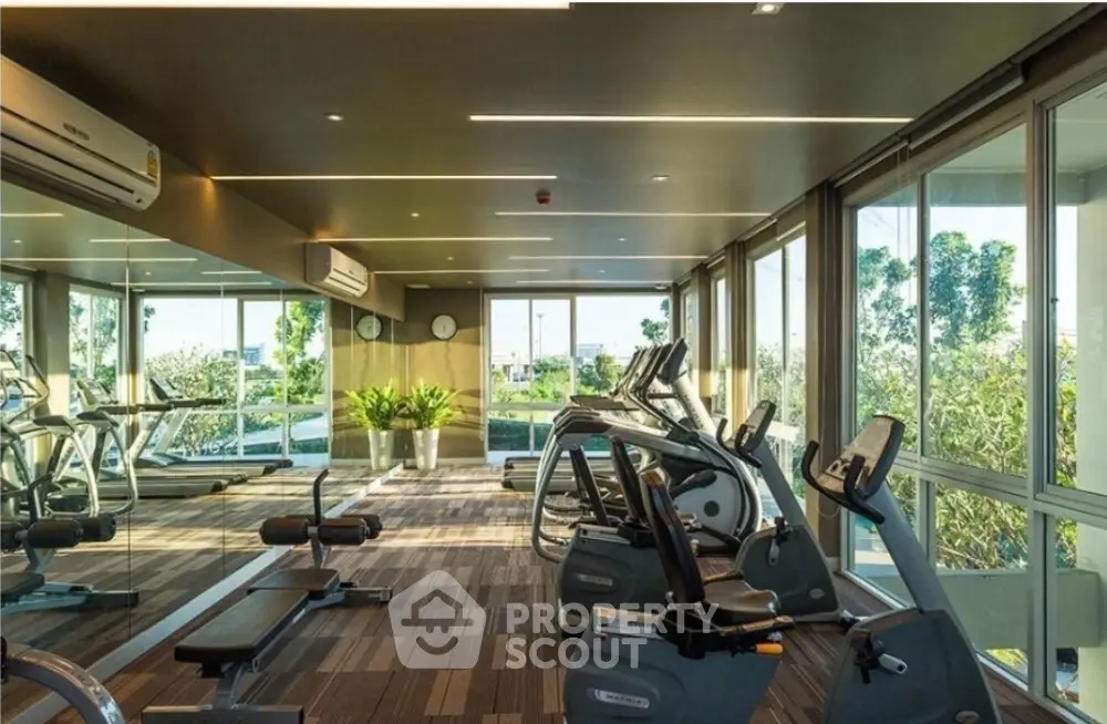 Modern gym with large windows and fitness equipment in a luxury apartment building.