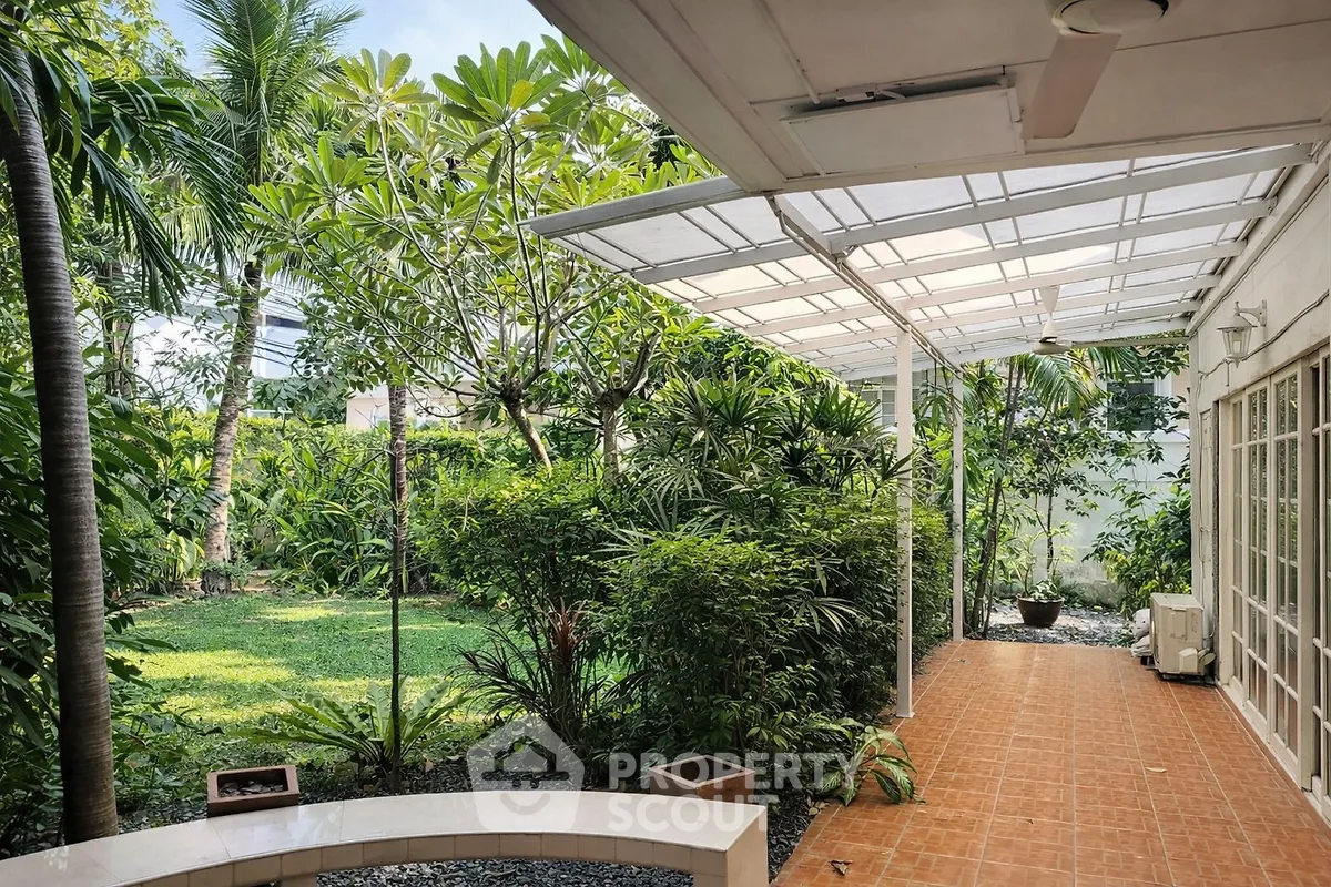 Charming garden view with lush greenery and covered patio, perfect for outdoor relaxation.