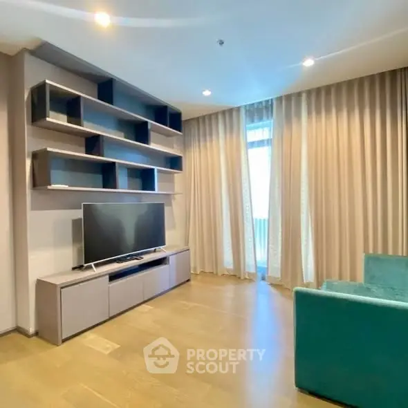 Modern living room with sleek shelving and large TV, featuring elegant curtains and cozy seating.