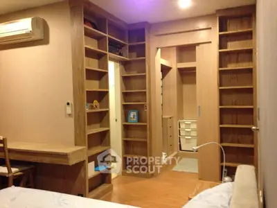 Spacious bedroom with built-in wooden shelves and modern air conditioning unit.
