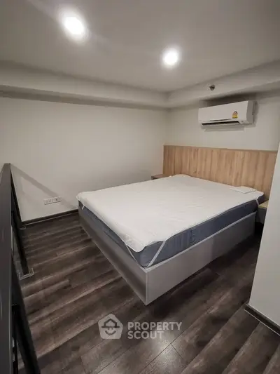 Modern bedroom with sleek wooden flooring and air conditioning, perfect for comfort and relaxation.