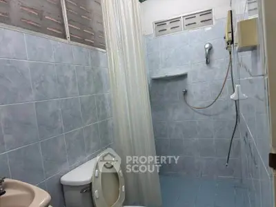 Compact bathroom with blue tiles and shower area in a cozy home.
