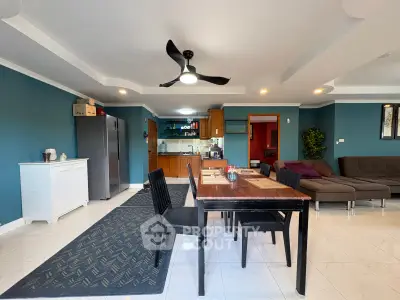 Spacious open-plan living room with modern kitchen and dining area, featuring stylish decor and ample natural light.