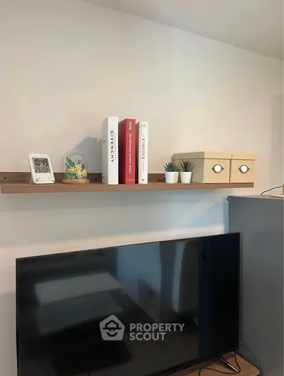 Modern living room with stylish shelf and TV setup, featuring decorative books and plants.
