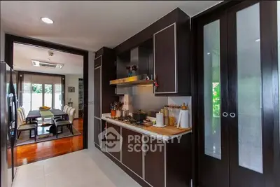 Modern kitchen with sleek cabinetry and open layout leading to dining area.