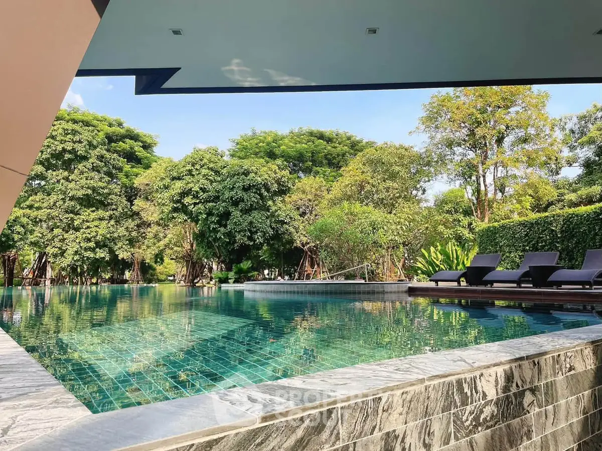 Luxurious outdoor pool with lush greenery and modern design, perfect for relaxation and leisure.
