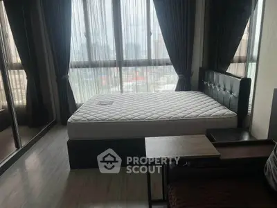 Spacious bedroom with large windows and city view, featuring a comfortable bed and modern decor.