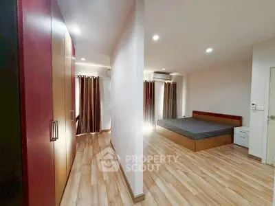 Spacious bedroom with wooden flooring and ample natural light