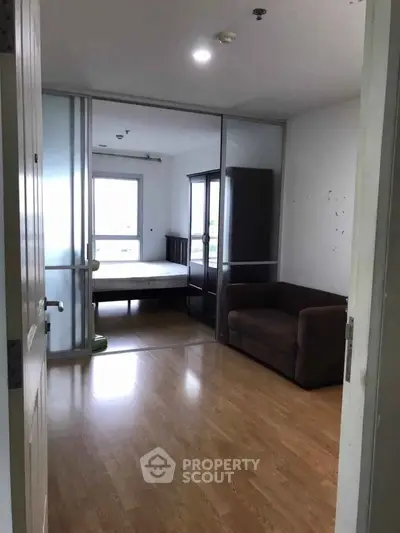 Spacious bedroom with wooden flooring and sliding glass doors in modern apartment.