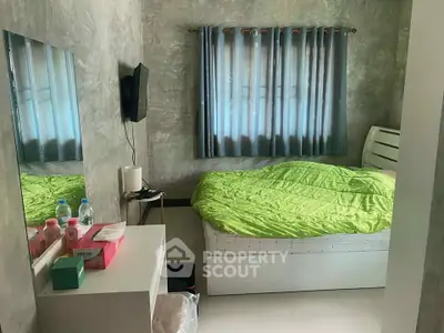 Cozy bedroom with modern decor and green bedding, featuring a wall-mounted TV and stylish curtains.