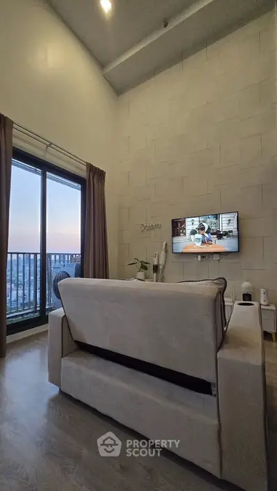 Modern living room with high ceiling and balcony view at sunset