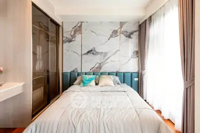 Luxurious bedroom with marble accent wall and elegant curtains in modern apartment.
