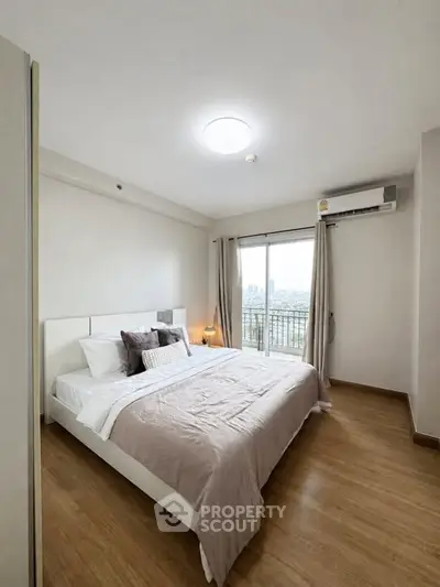 Spacious bedroom with city view and modern decor in a high-rise apartment.