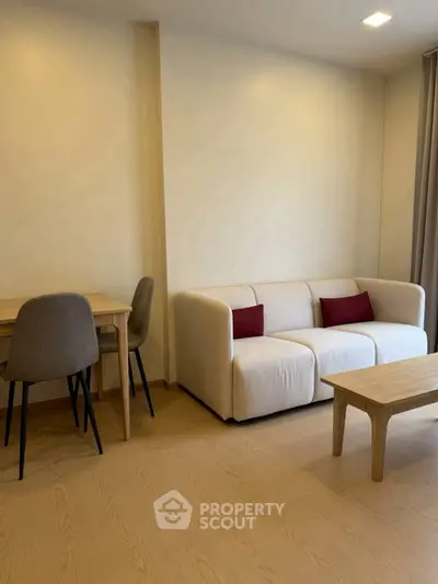 Modern living room with cozy sofa and dining area, featuring minimalist wooden furniture and warm lighting.