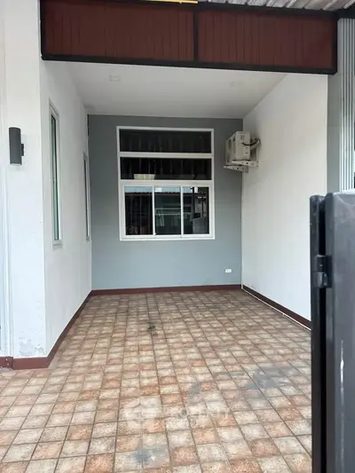 Charming covered patio with tiled flooring and large window, perfect for outdoor relaxation or storage.