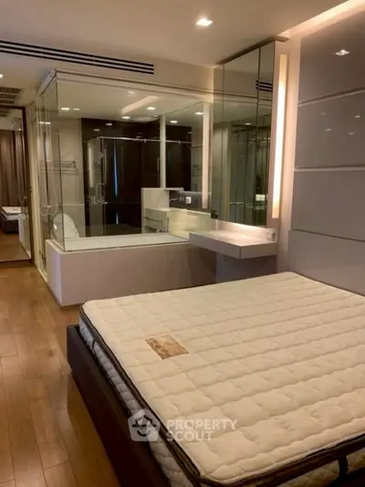 Luxurious bedroom with modern ensuite bathroom and elegant wooden flooring.