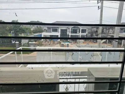 View from a window overlooking a suburban street with modern houses and greenery.