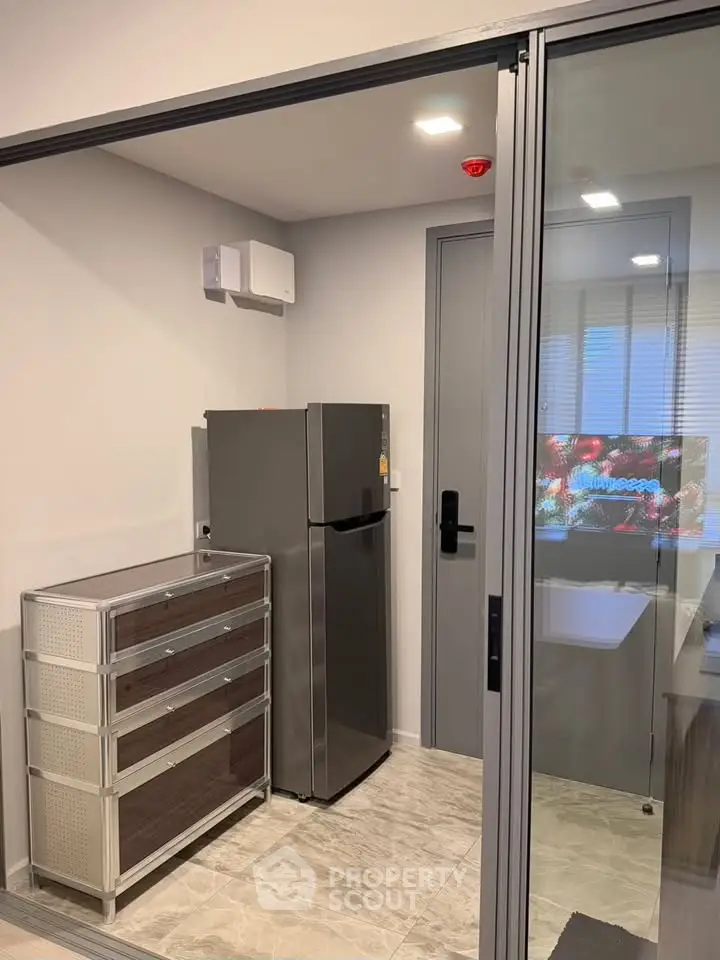 Modern kitchen with sleek fridge and storage drawers in compact space.