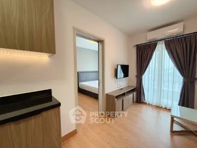 Modern apartment interior with bedroom and living area, featuring wood flooring and natural light.