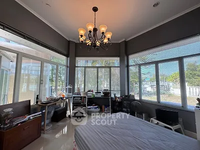 Spacious bedroom with large windows and elegant chandelier, offering a serene view.