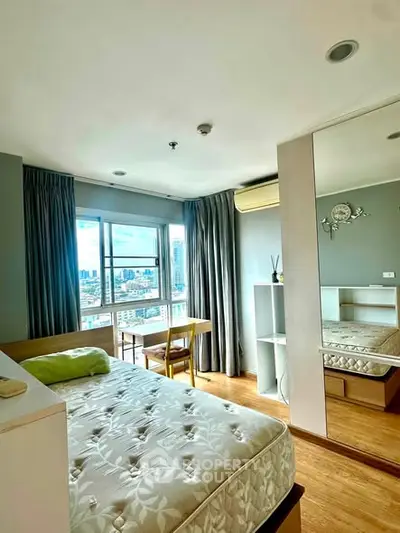 Bright bedroom with city view, featuring a comfortable bed, wooden flooring, and ample natural light.