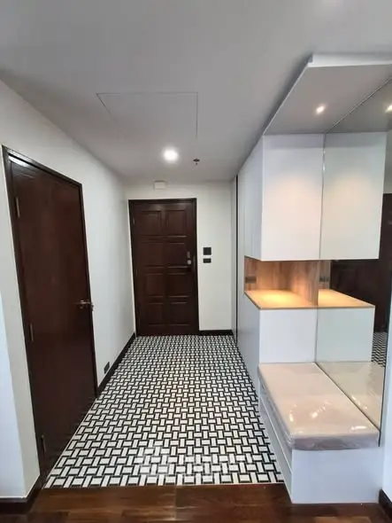 Modern apartment entrance with stylish geometric floor tiles and sleek cabinetry.
