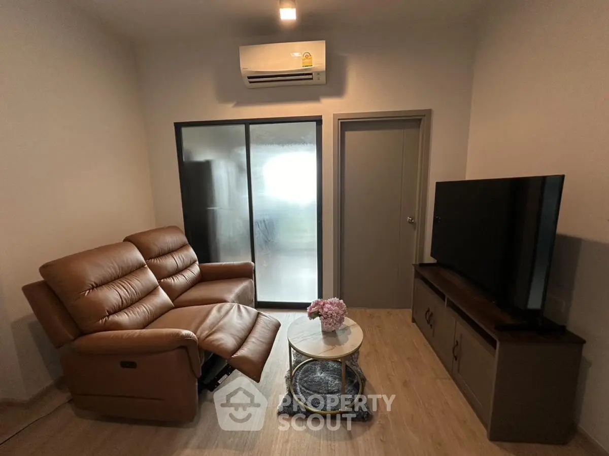 Cozy living room with brown leather recliner, large TV, and air conditioning, perfect for relaxation.