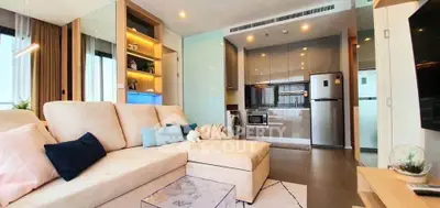Modern living room with open kitchen, featuring sleek appliances and cozy seating area.