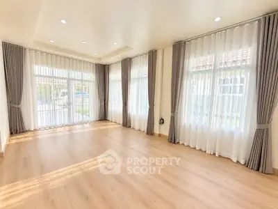 Spacious sunlit living room with elegant curtains and hardwood flooring