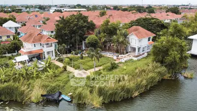 Charming waterfront homes with red-tiled roofs and lush greenery in a serene neighborhood.