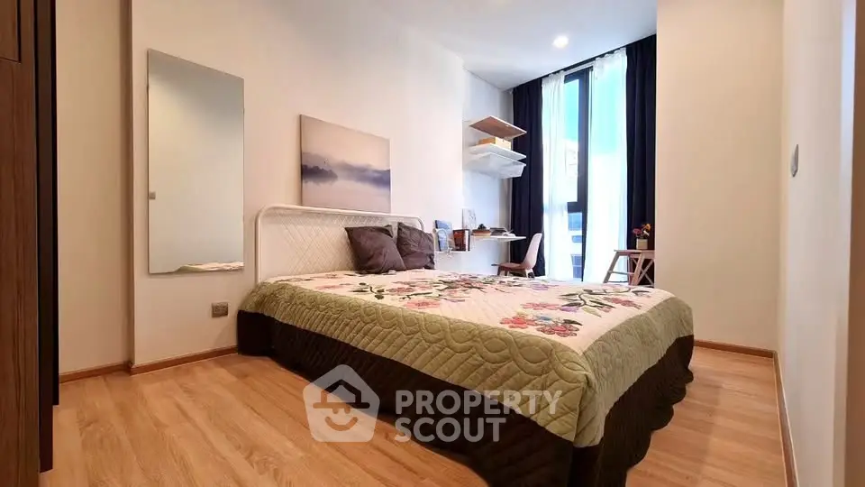 Cozy bedroom with modern decor and natural light, featuring a stylish workspace and elegant wooden flooring.